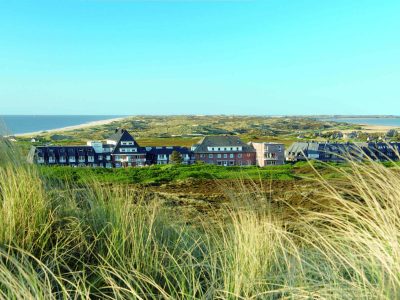 Landschaftsbild mit Küste, Dünen und Hotel Rungholt