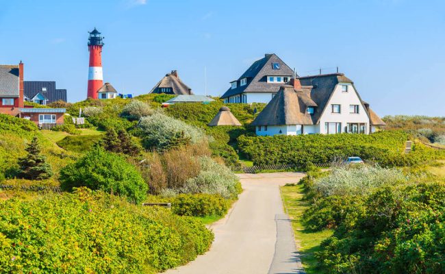 Idyllische Lanschaftsszene auf Sylt mit Leuchtturm und Reethäusern