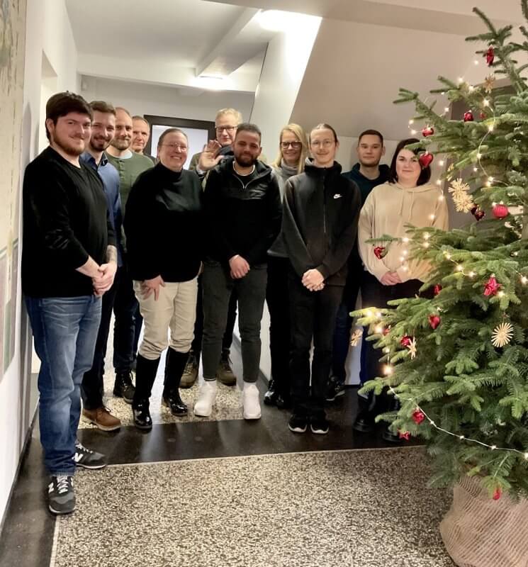 Mitarbeiter-Gruppenfoto neben dem Weihnachtsbaum im Flur aus dem Jahr 2022